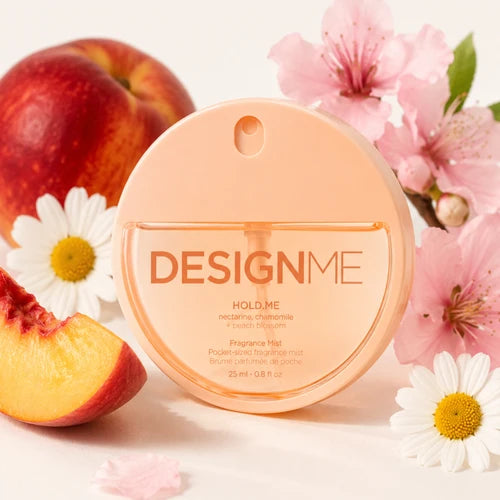Brume parfumé rond de couleur orange écrit Design me de la gamme hold me démontrant autour des pêches et des fleurs pour l'odeur